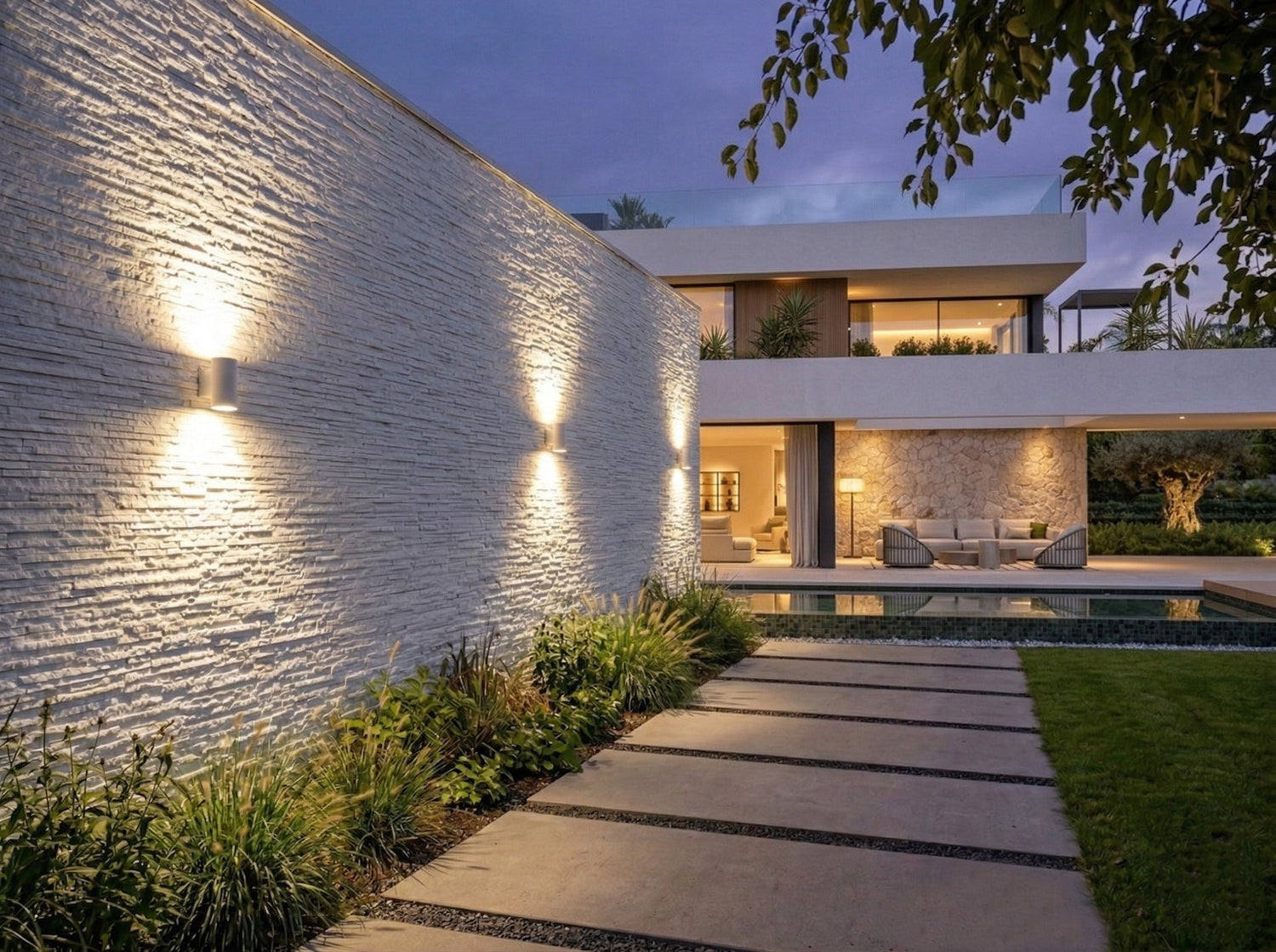 Modern villa exterior with textured stone wall tiles, outdoor facade cladding, landscape pathway design, and architectural lighting by Roman Mosaic, premium wall tile supplier UAE.