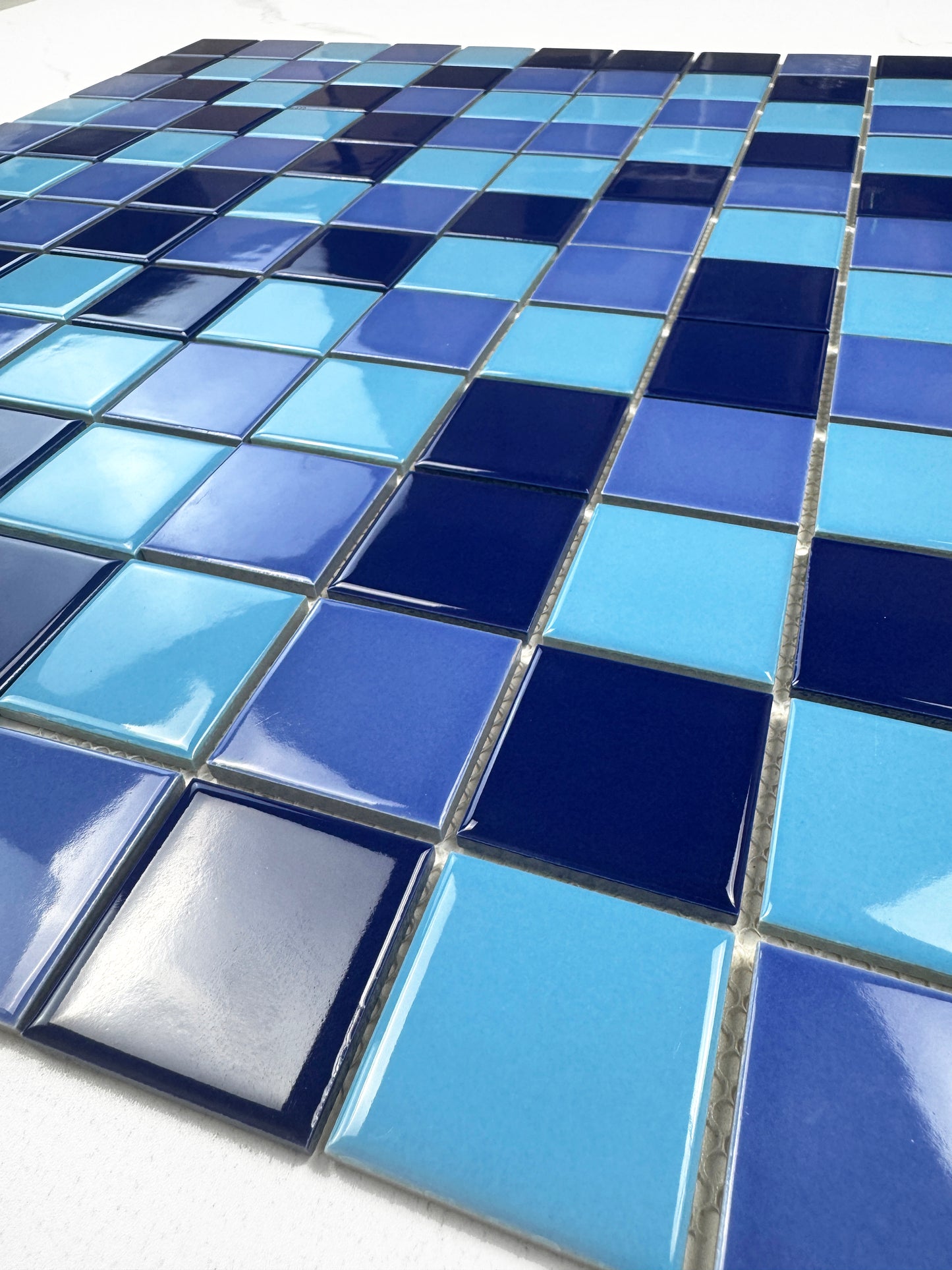 Close-up of blue and turquoise mosaic tiles on a white surface
