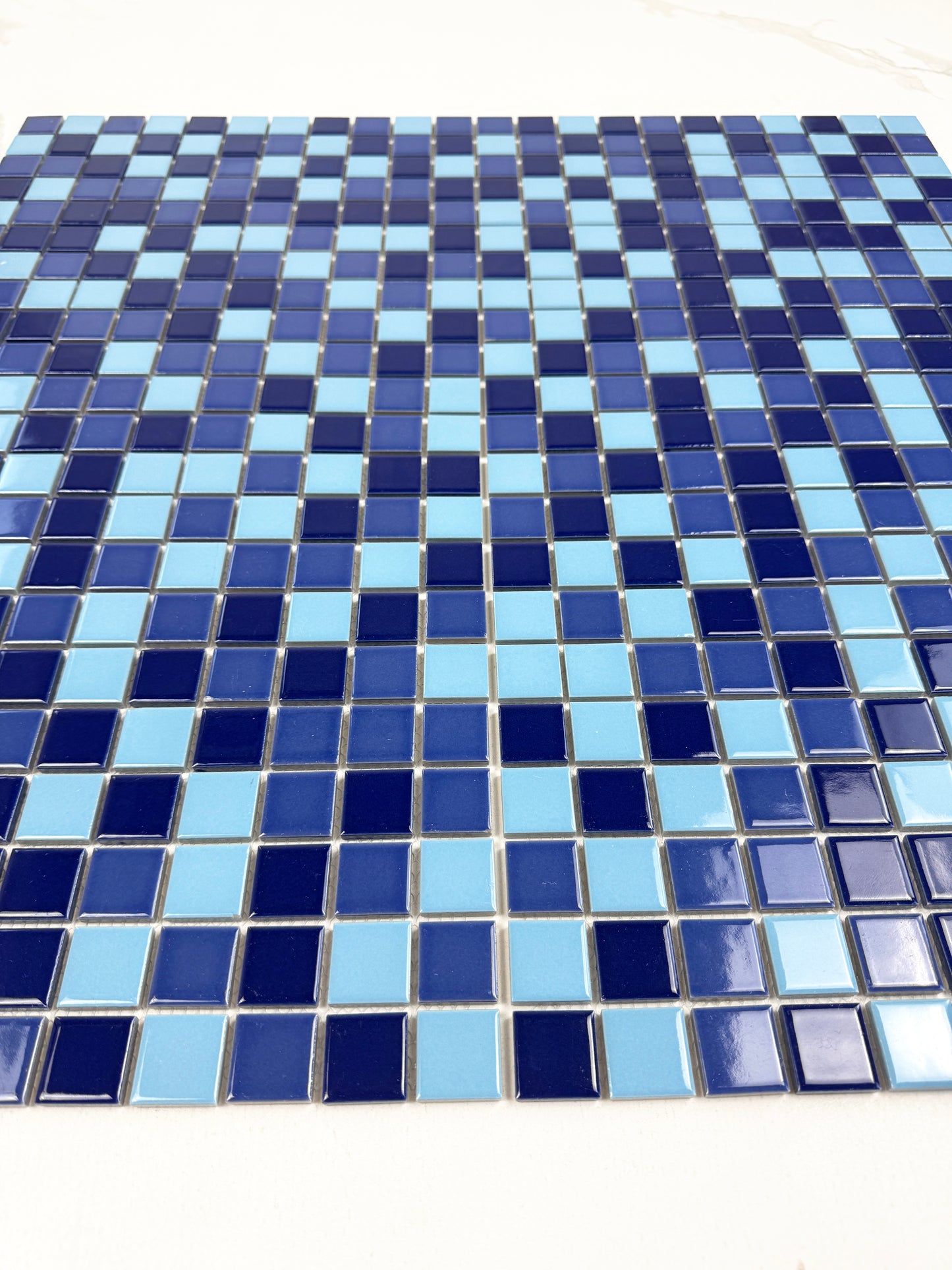 Mosaic pattern of blue and light blue tiles on a white background