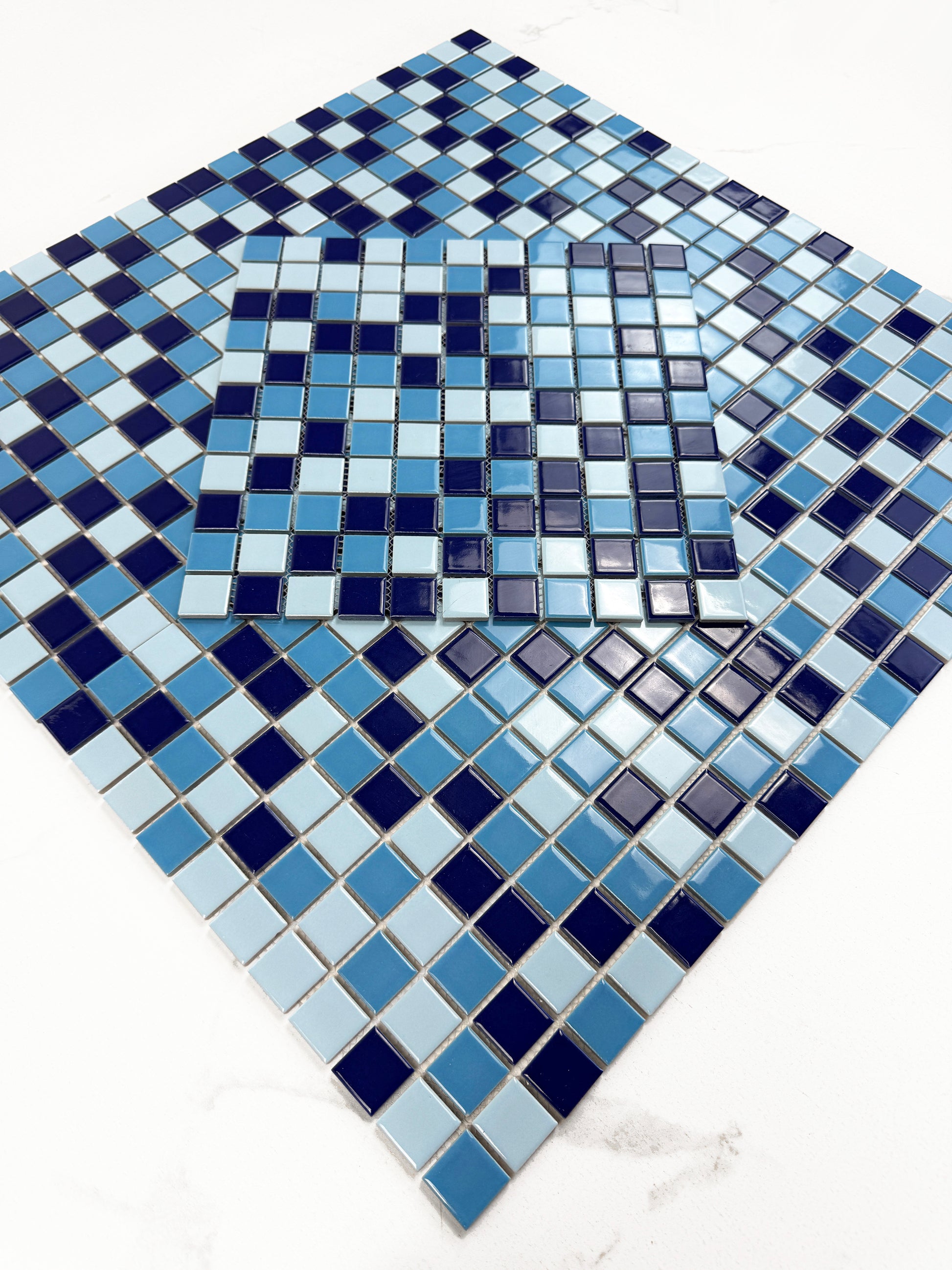 Mosaic pattern of blue and black tiles on a white background